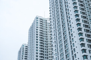 Obraz premium Low angle photo of an apartment building or high-rise residential building in the Pluit area, North Jakarta, Indonesia with bright sky background. Empty blank copy text space