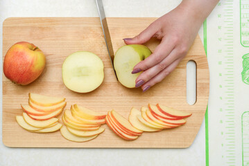 Slicing apples on a wooden cutting board with knife and hand in view.