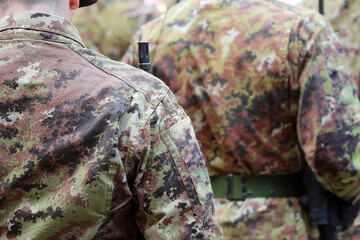 many soldiers standing at attention wearing camouflage uniforms