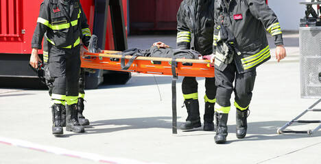 Firefighters carry a stretcher with a seriously injured person after a disaster to the hospital