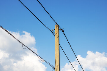 A tall telephone pole stands against a vast blue sky backdrop