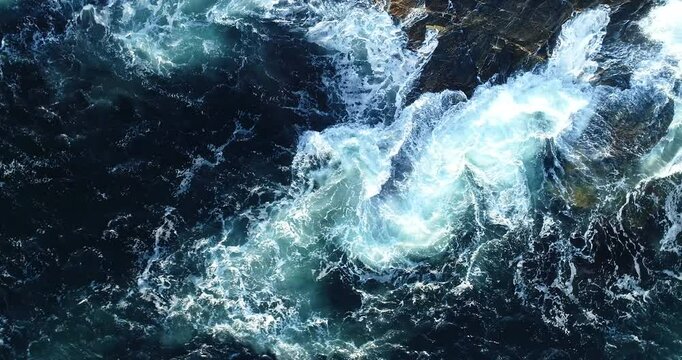Aerial shot of dramatic waves crashing against the sharp, rocky Norwegian coastline.