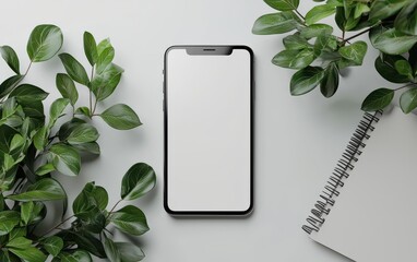 Mockup of a blank phone screen on a white background surrounded by green leaves and a spiral notebook for digital design projects