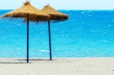 Two beach umbrellas are on the beach
