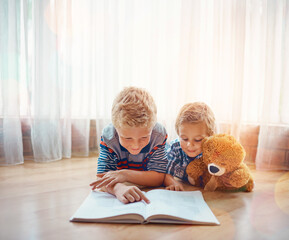 Reading, teddy bear and children with book on floor in home for bonding, learning or knowledge. Happy, relax and boy kids or siblings with fantasy novel, story or literature together with plush toy.