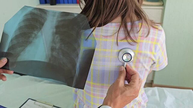 Pediatrician listens to lungs of small child girl with stethoscope 