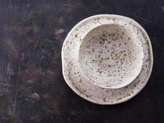 Table setting. White craft plate at dark slate table. Dark food background. Top view copy space.