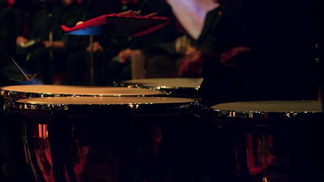 Drummer playing timpani drums in a musical orchestral concert.