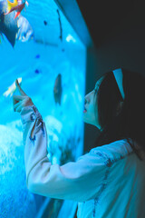 水族館の水槽を指をさしながら眺める女性