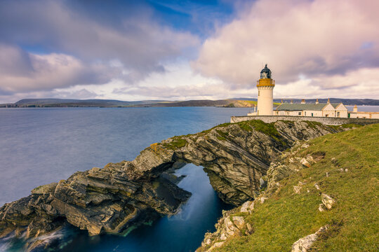 Bressay Lighthouse and a natural arch in the rock below it in the Shetland Islands