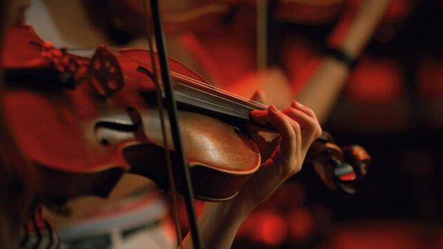 Violinists playing a fast tone ending an orchestral symphony in a concert.