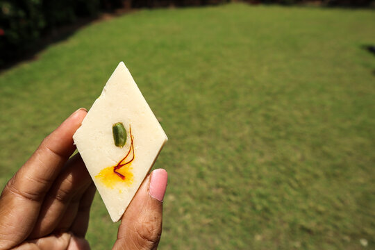 Delicious Badam katli sweet in hand. Badam katli, Kaju katli with pasta and saffron garnishing