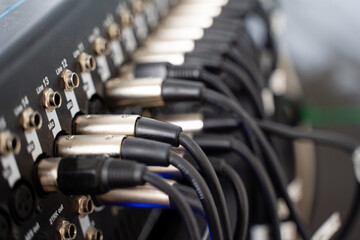 A closeup view of intricate audio mixer connections, highlighting various cables and connectors...