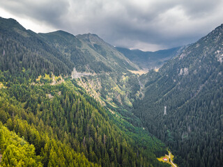 Stunning aerial shot of Romania&rsquo;s Transfagarasan road nestled in green, misty mountains.