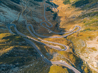 Drone view of the scenic Transfagarasan highway in the fall, capturing cars amid a breathtaking autumn landscape.