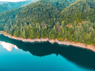 Drone perspective of a sunset casting vibrant colors over a lake and mountains, creating a breathtaking natural palette.