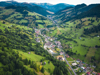 Aerial view of a panoramic landscape surrounded by mountains on the horizon, featuring lush green meadows.