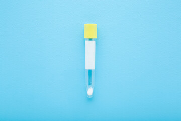 Empty transparent plastic tube for urine or other analysis test on light blue table background. Pastel color. Healthcare concept. Closeup. Top down view.