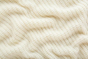 Light white wavy soft knitted fabric background. Closeup. Top down view.