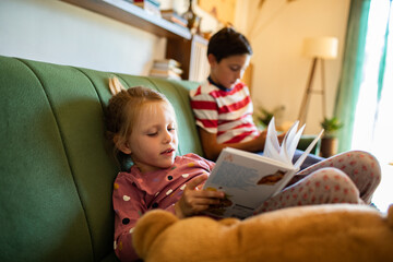 Kids reading books on the couch at home