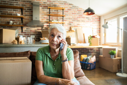 Senior woman on phone while labeling moving boxes in new home