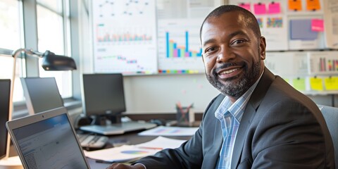 Cheerful man in an office working on a laptop and researching online for a creative project at a digital agency, focused on internet and networking for investment opportunities