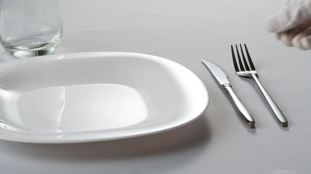 Fancy restaurant, waiter Elegant table setting with white square plate and silverware, arranged for sophisticated dining