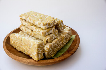 A stack of sliced raw tempeh on a wooden plate.