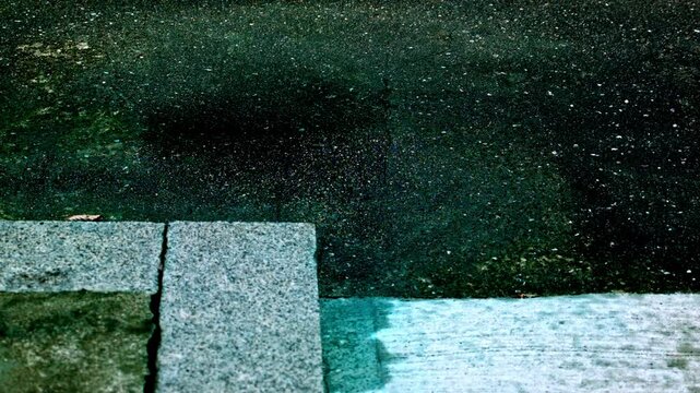 にわか雨がアスファルトや石の硬い地面に降って滴が跳ねる