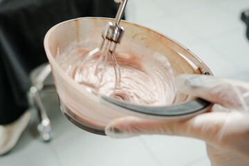 a beautiful young girl with short hair and a bob haircut is doing a procedure in a beauty salon. Hair master doing coloring and tone to client's hair close-up