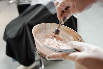a beautiful young girl with short hair and a bob haircut is doing a procedure in a beauty salon. Hair master doing coloring and tone to client's hair close-up