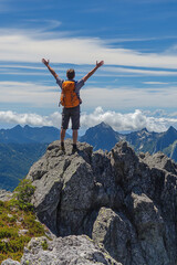 Fototapeta premium A hiker standing on a mountain peak with arms raised