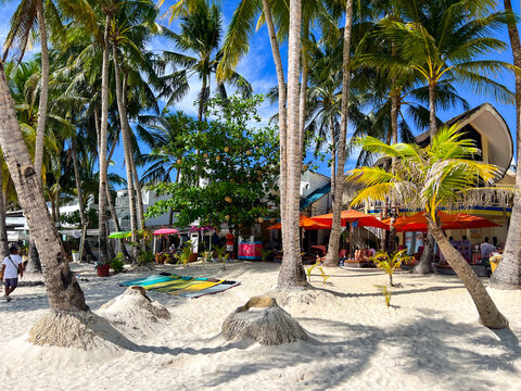 Buildings on a White beach, Boracay seen through the palm trees 