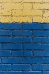 Fototapeta premium Brightly painted brick wall featuring yellow and blue sections in a vibrant urban setting