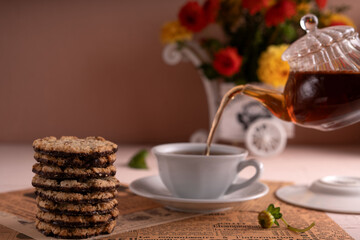 photo, round, chocolate, filled,photo, cookie, left, side, piece, paper, newspaper, print, white, teacup, matching, stack, saucer, middle, tea, glass,