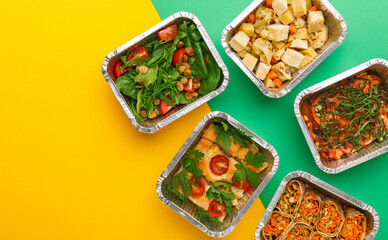 Healthy meals delivery. Casserole, vegetarian rolls, fresh and baked vegetables salads in foil take away boxes on abstract bright background. Eating right concept, copy space, top view.