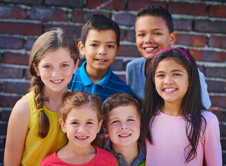 Happy, friends and portrait of children by brick wall for playing, bonding and fun together outdoors. School, diversity and young boys and girl smile for learning, education and development on campus