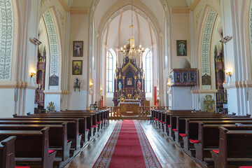 The interior of the church. The altar inside the Catholic church. Icons on the white walls. Places for temple visitors to pray.