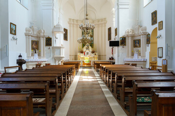 The interior of the church. The altar inside the Catholic church. Icons on the white walls. Places for temple visitors to pray.