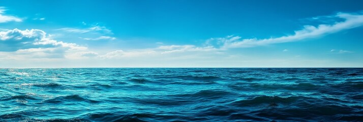 Fototapeta premium A serene seascape showcasing the vast expanse of the ocean meeting the horizon under a clear blue sky dotted with fluffy clouds. The tranquil scene evokes a sense of peace and tranquility, representin