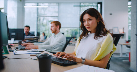 Multi-ethnic managers working together in business office. People sitting at tables with computers and analyzing electronic data on screens. Corporate software. Management. Financial company.