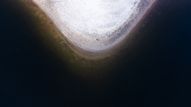Plage de sable se jetant dans le lac dont l'eau est tr&egrave;s sombre. Eau du lac qui semble engloutir le sable petit &agrave; petit.