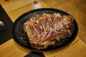 Traditional Spanish rib eye steak on the bone Chuleton, cooked over charcoal and sliced to share, served in a restaurant