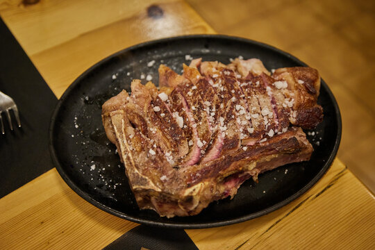 Traditional Spanish rib eye steak on the bone Chuleton, cooked over charcoal and sliced to share, served in a restaurant