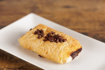 Detailed portrait of a Neapolitan filled with white and milk chocolate. Sweet dessert with lots of sugar and calories on a white plate.