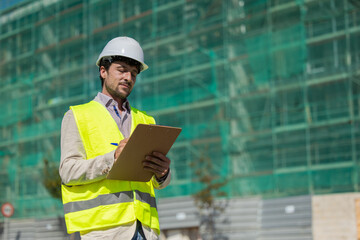 Fototapeta premium Construction manager or architect with reflective vest white helmet reviewing the construction of homes, safety inspector reviewing work, work safety real estate future professions, housing project