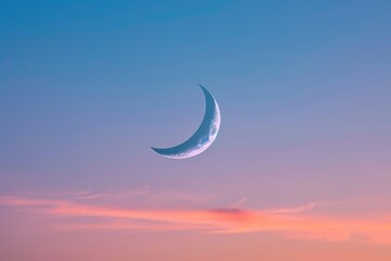 A picture of a crescent moon visible in the sky during a beautiful sunset