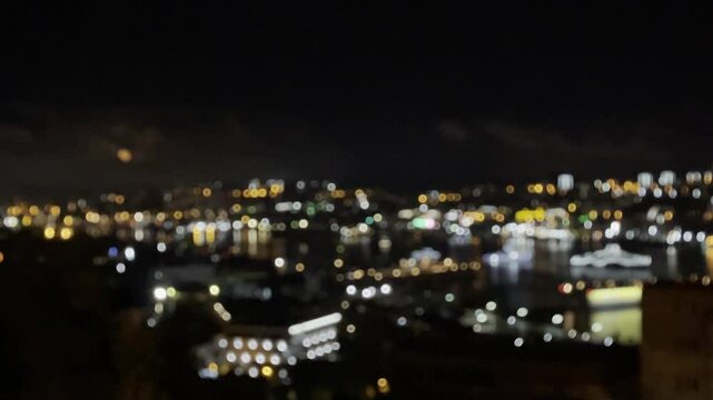 Bokeh blurred twinkling night city lights from buildings near bay water