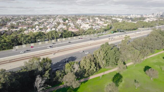 Cars And Trains Running Through The Freeway With Perth Central Business District In The Distance In Australia. - aerial shot