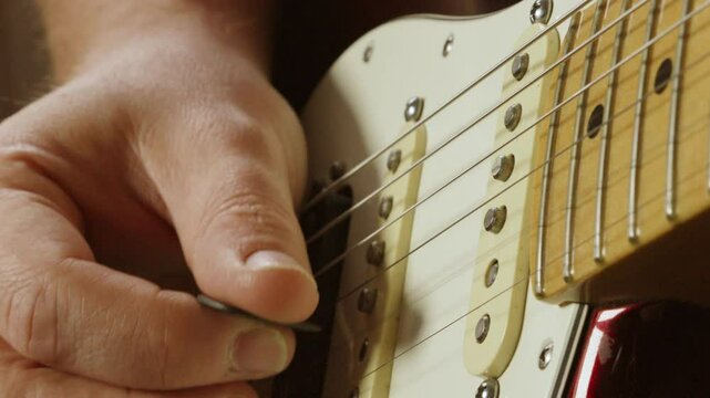 Close Up on Pickups of Stratocaster Guitar As Guitarist Plucks Strings with Plectrum and Twangs on Higher Chord Notes 4K